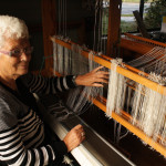 Kobi Brinkman demonstrates the begining of weaving at her loom.