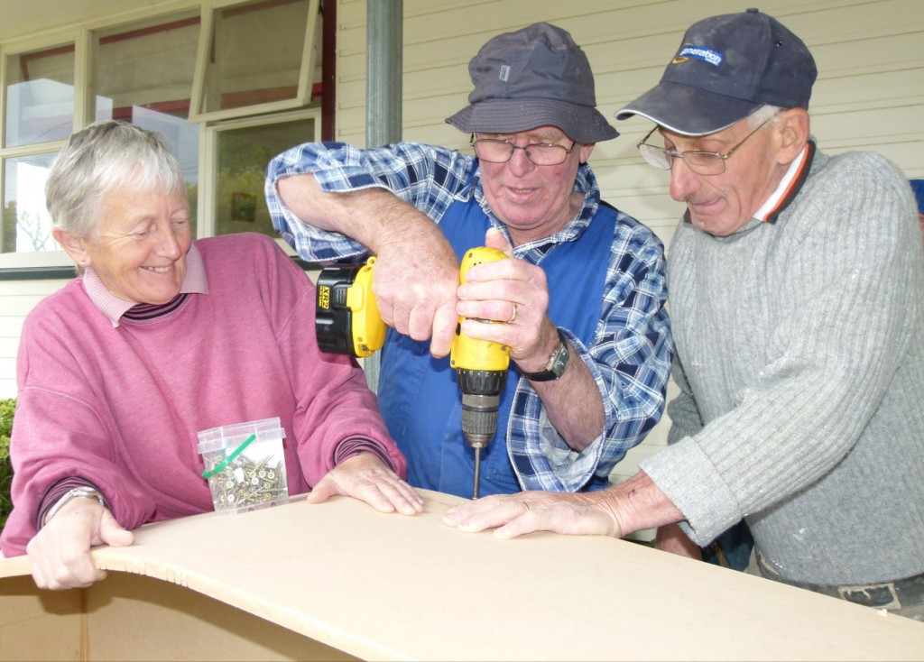 Well drilled: Volunteer builders Chris Mills, left, Graeme Lyford and Bill Sharpe drill on the coffin walls. 