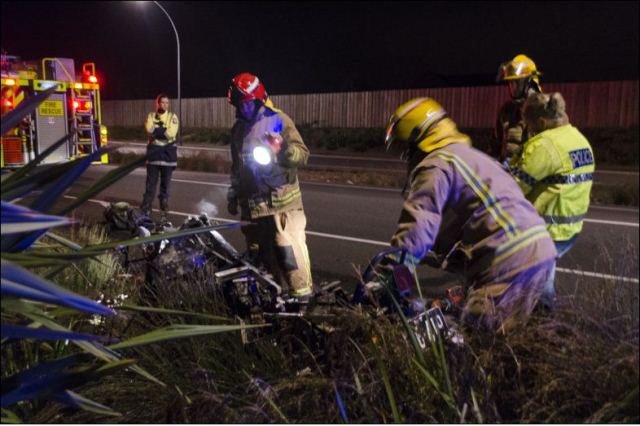 BURN OUT: Firefighters check over the remains of the smouldering motorcycle. Photo: Rich Garratt